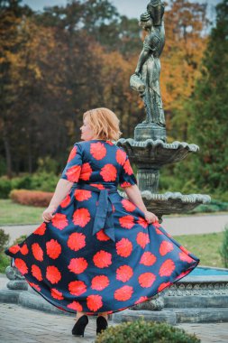 Klasik görünümlü orta yaşlı kadın parka bakıyor, tombul bayanlar için şık bir tarz. Olgun moda artı boyut kadın, orta yaşlı kadın yaşam tarzı kavramı.