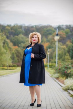 Klasik görünümlü orta yaşlı kadın parka bakıyor, tombul bayanlar için şık bir tarz. Olgun moda artı boyut kadın, orta yaşlı kadın yaşam tarzı kavramı.