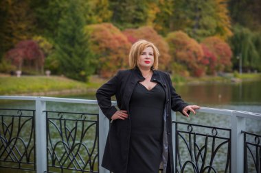 Klasik görünümlü orta yaşlı kadın parka bakıyor, tombul bayanlar için şık bir tarz. Olgun moda artı boyut kadın, orta yaşlı kadın yaşam tarzı kavramı.