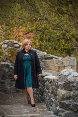 Klasik görünümlü orta yaşlı kadın parka bakıyor, tombul bayanlar için şık bir tarz. Olgun moda artı boyut kadın, orta yaşlı kadın yaşam tarzı kavramı.