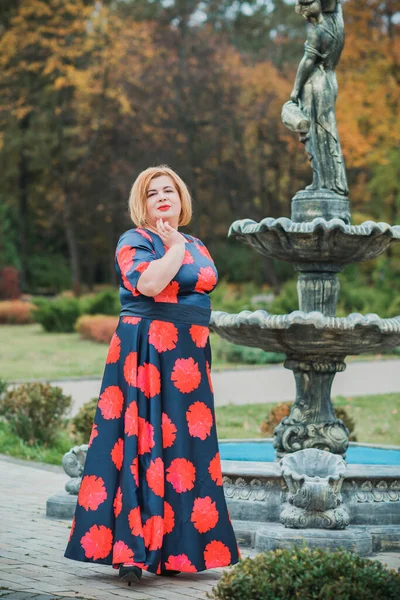 Middle age woman in classical look at park, fashionable style for plump ladies. Mature fashionable plus size woman, concept of middle age lady lifestyle