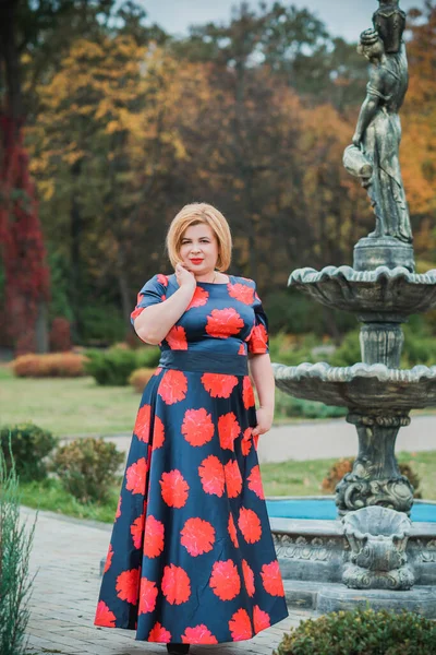 Middle age woman in classical look at park, fashionable style for plump ladies. Mature fashionable plus size woman, concept of middle age lady lifestyle