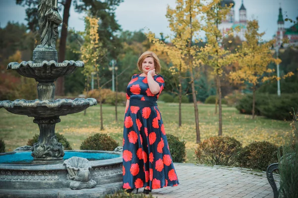 Middle age woman in classical look at park, fashionable style for plump ladies. Mature fashionable plus size woman, concept of middle age lady lifestyle