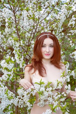 Genç, çekici, kızıl saçlı, dantelli iç çamaşırlı bir kız reklamını yapıyor. Porselen tenli. 