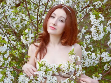 Genç, çekici, kızıl saçlı, dantelli iç çamaşırlı bir kız reklamını yapıyor. Porselen tenli. 