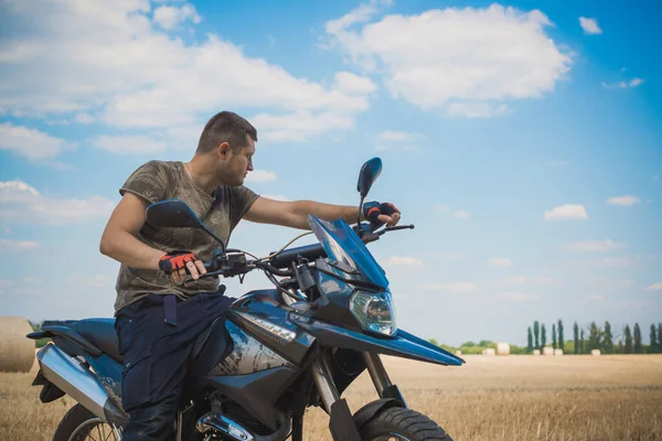 Young man on a motorcycle at field, hobby of modern people, lifestyle