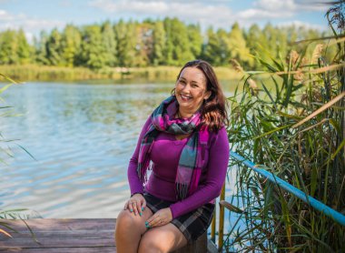 Sonbaharda gülümseyen güzel ve büyük beden modeli. Güzel bir sonbahar gününde gülümseyen büyük kızı kapatıyoruz. Yeni çağın standart güzelliğinin fotoğrafı.