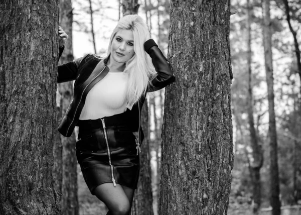森林里一个性感的年轻女人穿着皮夹克 裙子在森林里衬托着松树衬托着自己和衣服 — 图库照片