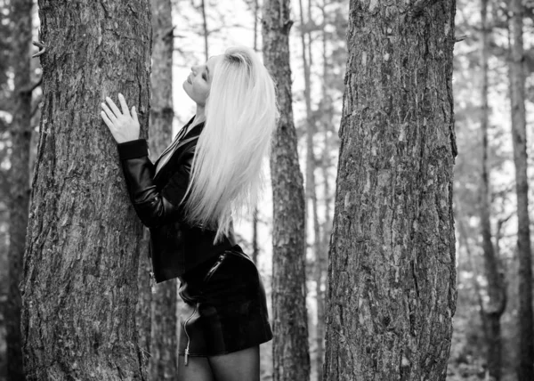 森林里一个性感的年轻女人穿着皮夹克 裙子在森林里衬托着松树衬托着自己和衣服 — 图库照片