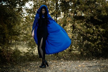 Cadılar Bayramı zamanı, cadılık, modern gotik kız mavi pelerinli kutlama. Fotoşoplar ve kostüm için iyi fikirler