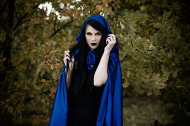 Cadılar Bayramı zamanı, cadılık, modern gotik kız mavi pelerinli kutlama. Fotoşoplar ve kostüm için iyi fikirler