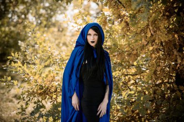 Cadılar Bayramı zamanı, cadılık, modern gotik kız mavi pelerinli kutlama. Fotoşoplar ve kostüm için iyi fikirler