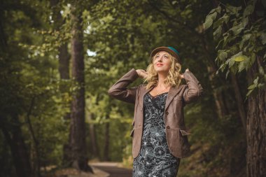 Sonbaharda modaya uygun giyinen, moda konsepti olan orta yaşlı bir kadınla parkta sahne alan bir kadın.