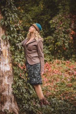 Sonbaharda modaya uygun giyinen, moda konsepti olan orta yaşlı bir kadınla parkta sahne alan bir kadın.