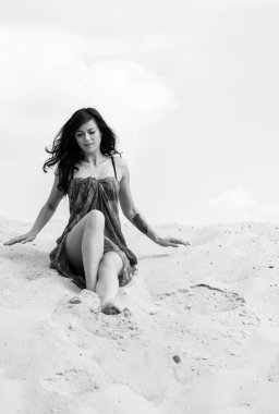 Kumsalda bir kız, kumların kumullarında dinleniyor ve dinleniyor. Güzel bir kadın hem iyi bir vücut hem de kendini gösterir. Güzel bir tatil ve ruhun ve bedenin güzelliği kavramı.