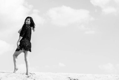 Kumsalda bir kız, kumların kumullarında dinleniyor ve dinleniyor. Güzel bir kadın hem iyi bir vücut hem de kendini gösterir. Güzel bir tatil ve ruhun ve bedenin güzelliği kavramı.