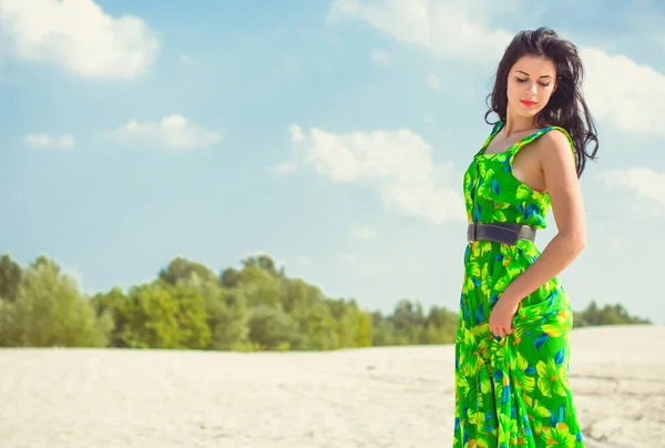 美丽的女人穿着绿色的夏装 穿着花纹 躺在沙漠的沙滩上 色彩艳丽的服装和时尚的外观 — 图库照片