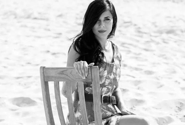 Beautiful woman on the sand in the desert in a green summer dress with patterns. Bright clothes and style for an all-day stylish look.