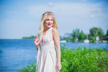 Sahilde beyaz Midi elbiseli zarif sarışın kadın. Beyaz kural, şık bayan, güzel elbise ve kıyafetler.