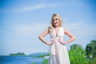 Sahilde beyaz Midi elbiseli zarif sarışın kadın. Beyaz kural, şık bayan, güzel elbise ve kıyafetler.