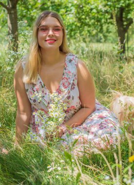 Çekici ve cüsseli genç bayan doğada dinleniyor. Şık giyinmiş genç bir kadının portresi.