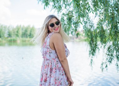 Çekici ve cüsseli genç bayan doğada dinleniyor. Şık giyinmiş genç bir kadının portresi.