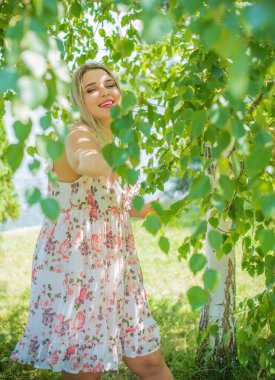 Çekici ve cüsseli genç bayan doğada dinleniyor. Şık giyinmiş genç bir kadının portresi.