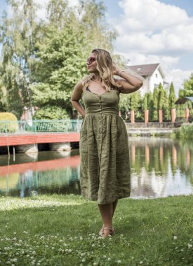 Çekici ve cüsseli genç bayan doğada dinleniyor. Şık giyinmiş genç bir kadının portresi.