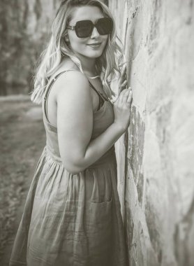 Çekici ve cüsseli genç bayan doğada dinleniyor. Şık giyinmiş genç bir kadının portresi.