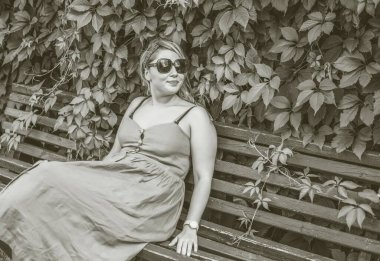 Çekici ve cüsseli genç bayan doğada dinleniyor. Şık giyinmiş genç bir kadının portresi.