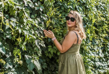 Çekici ve cüsseli genç bayan doğada dinleniyor. Şık giyinmiş genç bir kadının portresi.