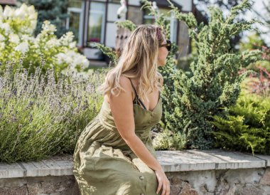 Çekici ve cüsseli genç bayan doğada dinleniyor. Şık giyinmiş genç bir kadının portresi.