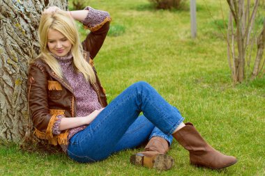 Doğada genç ve seksi sarışın kız ve nehir kenarında sazlıklar ve Amerikan kırsalında ağaçlar deri ceketli, mavi kazaklı, güzel yüzlü ve güzel gözlü kahverengi çizmeli.