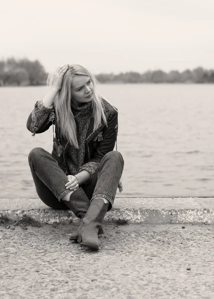 Doğada genç ve seksi sarışın kız ve nehir kenarında sazlıklar ve Amerikan kırsalında ağaçlar deri ceketli, mavi kazaklı, güzel yüzlü ve güzel gözlü kahverengi çizmeli.