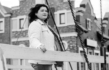 Yetişkin, iri yapılı, Amerikan ya da Avrupa görünümlü basit bir kadın şehirde hayatın tadını çıkarıyor. Fazla kilolu, ceketli ve fularlı hoş bir bayan şehrin eski bir köşesinde dolaşıyor.