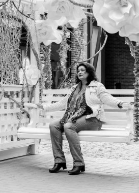 Yetişkin, iri yapılı, Amerikan ya da Avrupa görünümlü basit bir kadın şehirde hayatın tadını çıkarıyor. Fazla kilolu, ceketli ve fularlı hoş bir bayan şehrin eski bir köşesinde dolaşıyor.