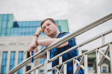 Ciddi ruh hali olan genç adam şehir manzarasına bak, tombul insanlar konsepti, büyük şehir hayatı. Şehir merkezindeki adamın resmi