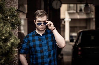 Ciddi ruh hali olan genç adam şehir manzarasına bak, tombul insanlar konsepti, büyük şehir hayatı. Şehir merkezindeki adamın resmi