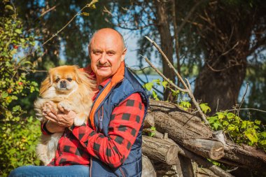 Emekli olmuş yaşlı bir adam, parkta gezintiye çıkmış kırmızı Pekin hayvanıyla köpek sever. Hayvanların sevgisini ve bakımını kavrayın. İyi insanlar evcil hayvanlara bakar.