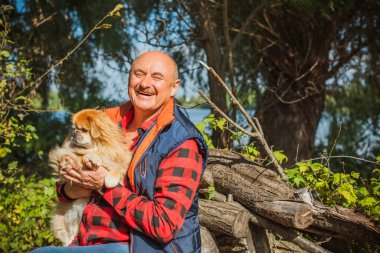 Emekli olmuş yaşlı bir adam, parkta gezintiye çıkmış kırmızı Pekin hayvanıyla köpek sever. Hayvanların sevgisini ve bakımını kavrayın. İyi insanlar evcil hayvanlara bakar.