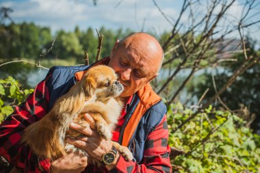 Emekli olmuş yaşlı bir adam, parkta gezintiye çıkmış kırmızı Pekin hayvanıyla köpek sever. Hayvanların sevgisini ve bakımını kavrayın. İyi insanlar evcil hayvanlara bakar.