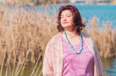 Çekici ve olgun bir kadının portresi. Güneşli bir sonbahar gününde gündelik tarzda yürüyüp bir şeyler düşünüyor. 40-50 yıl sonra kadın hayatı