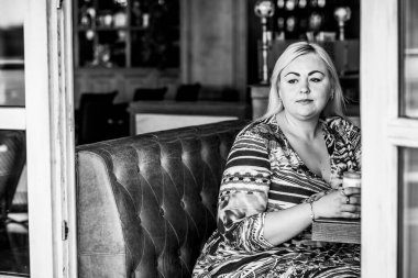 Restoranda genç, zarif, iri yarı bir kadın. Bayan randevuyu romantik bir havada bekler. Kalın vintage tonlarda portre