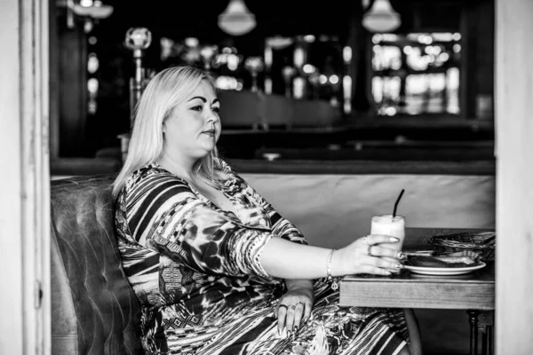 Restoranda genç, zarif, iri yarı bir kadın. Bayan randevuyu romantik bir havada bekler. Kalın vintage tonlarda portre