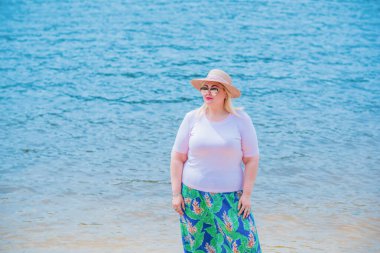 Artı plajda bir model. Şişman kadın hayattan zevk alıyor. Nehir kenarındaki doğada, kumların üzerinde dinlenen güzel bir kadın. Kadın hayatı kavramı.