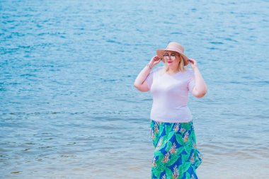 Artı plajda bir model. Şişman kadın hayattan zevk alıyor. Nehir kenarındaki doğada, kumların üzerinde dinlenen güzel bir kadın. Kadın hayatı kavramı.