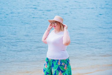 Artı plajda bir model. Şişman kadın hayattan zevk alıyor. Nehir kenarındaki doğada, kumların üzerinde dinlenen güzel bir kadın. Kadın hayatı kavramı.