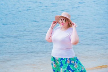 Artı plajda bir model. Şişman kadın hayattan zevk alıyor. Nehir kenarındaki doğada, kumların üzerinde dinlenen güzel bir kadın. Kadın hayatı kavramı.