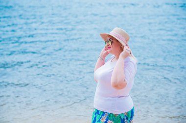 Artı plajda bir model. Şişman kadın hayattan zevk alıyor. Nehir kenarındaki doğada, kumların üzerinde dinlenen güzel bir kadın. Kadın hayatı kavramı.