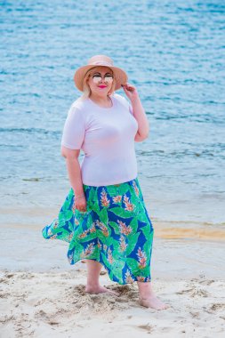 Artı plajda bir model. Şişman kadın hayattan zevk alıyor. Nehir kenarındaki doğada, kumların üzerinde dinlenen güzel bir kadın. Kadın hayatı kavramı.